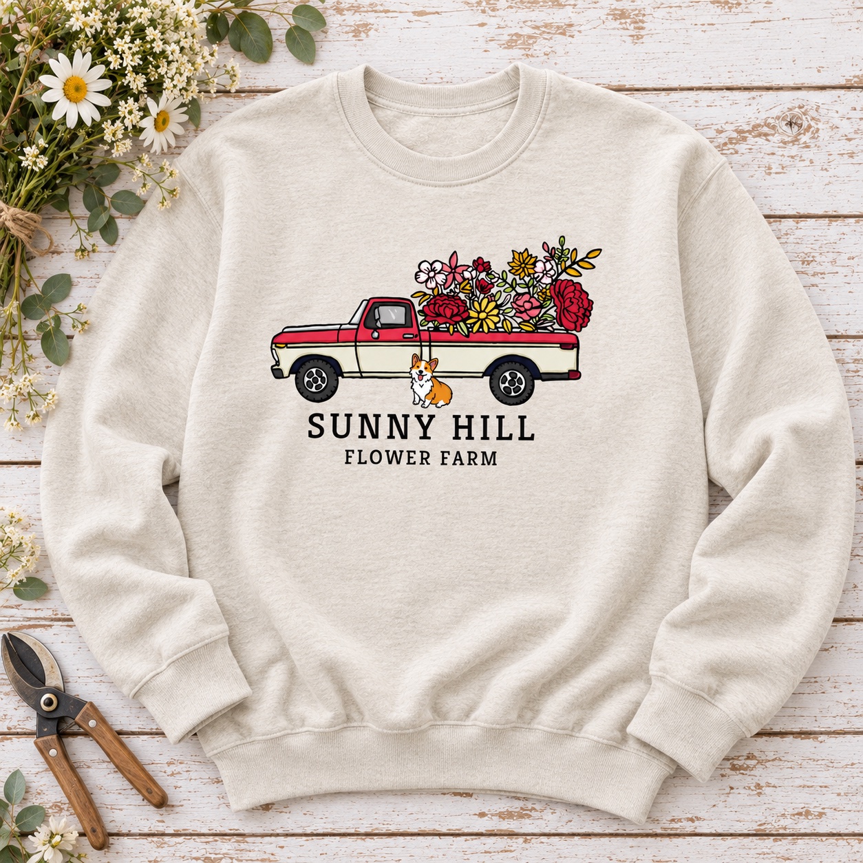 Styled flat-lay mockup of a cream crewneck sweatshirt with Micah’s Sunny Hill Flower Farm artwork