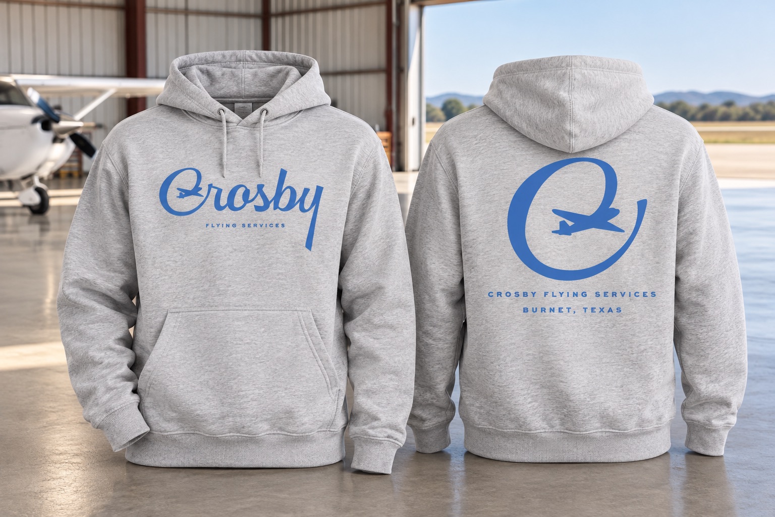 Staged front and back Crosby Flying Services hoodies in an aircraft hangar